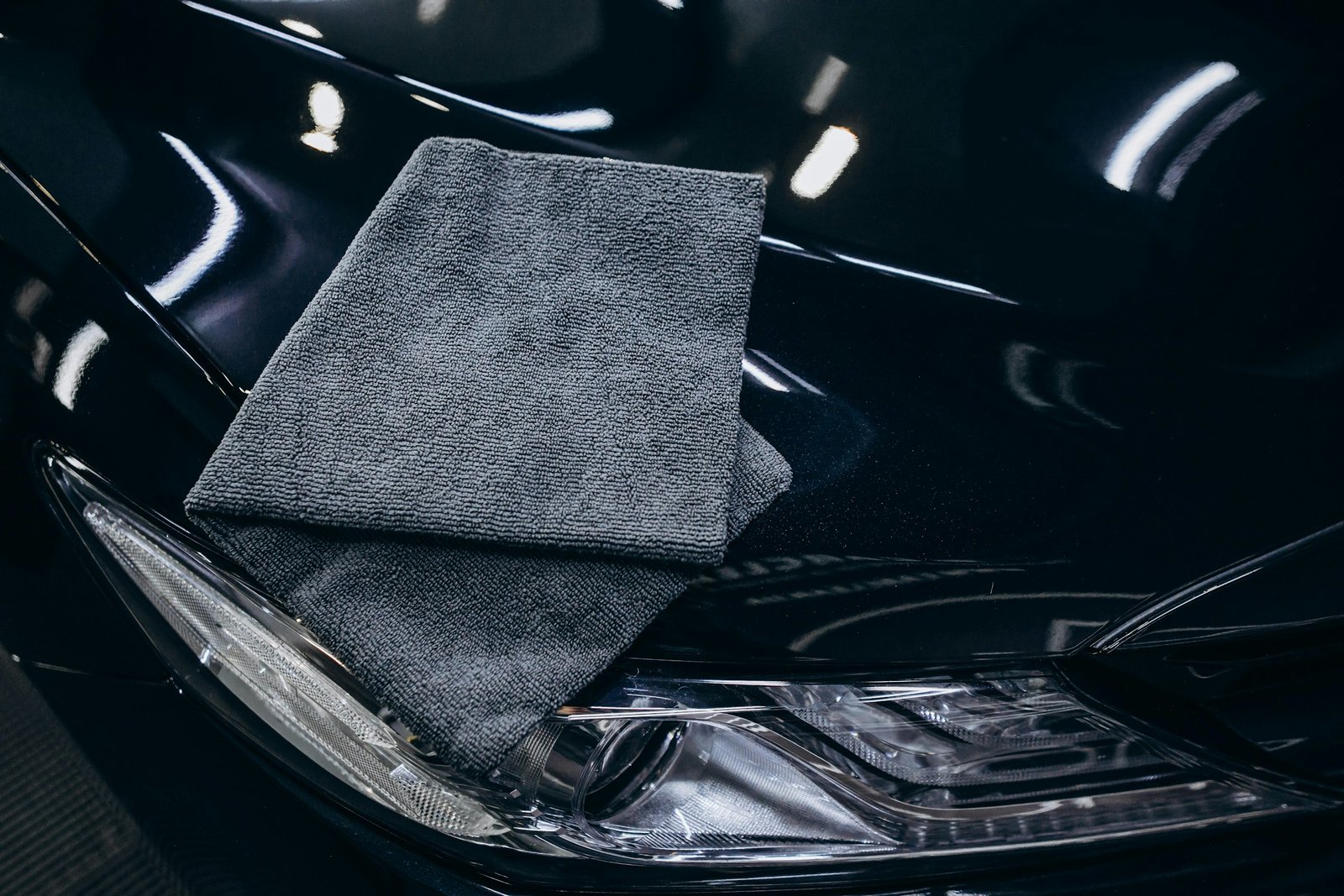 Soft grey microfiber towel on a car hood, used for safe hand car detailing